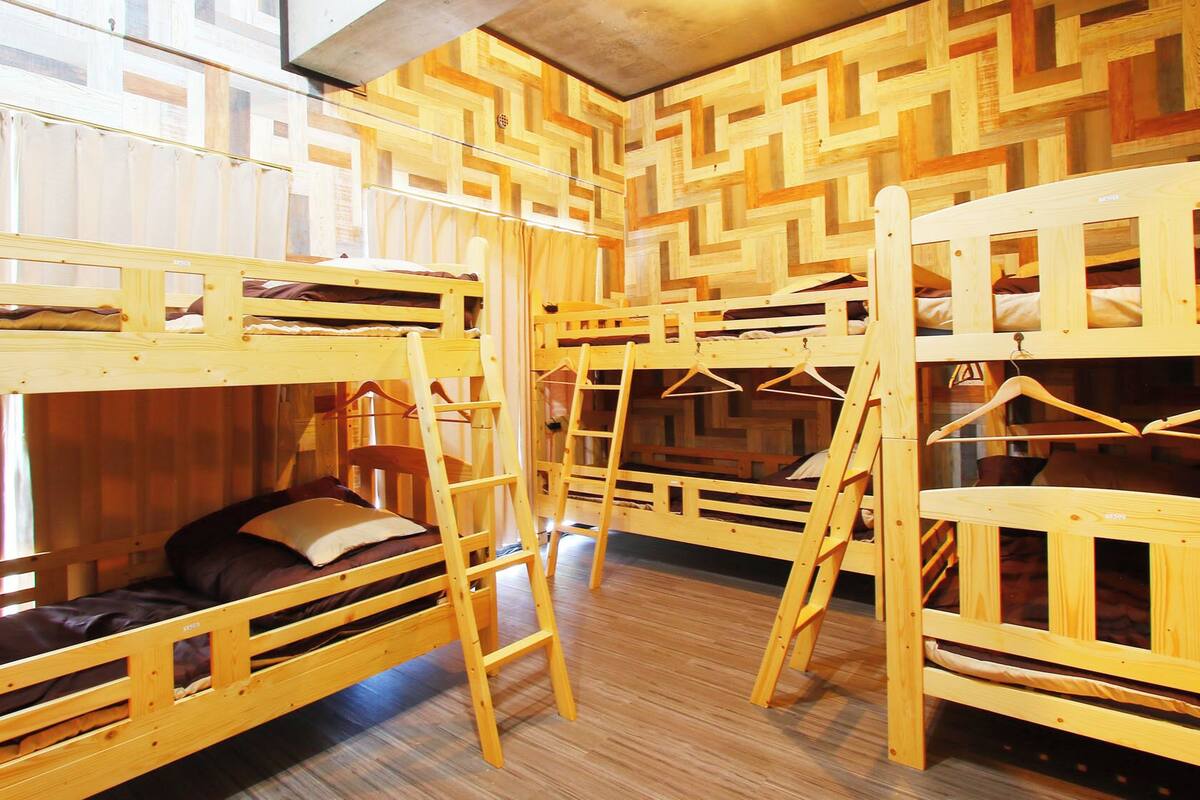 A room with bunk beds, wooden walls, and a window.