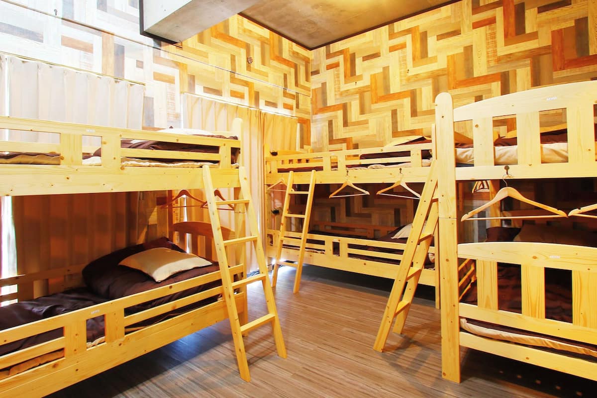 A room with bunk beds, wooden walls, and a window.