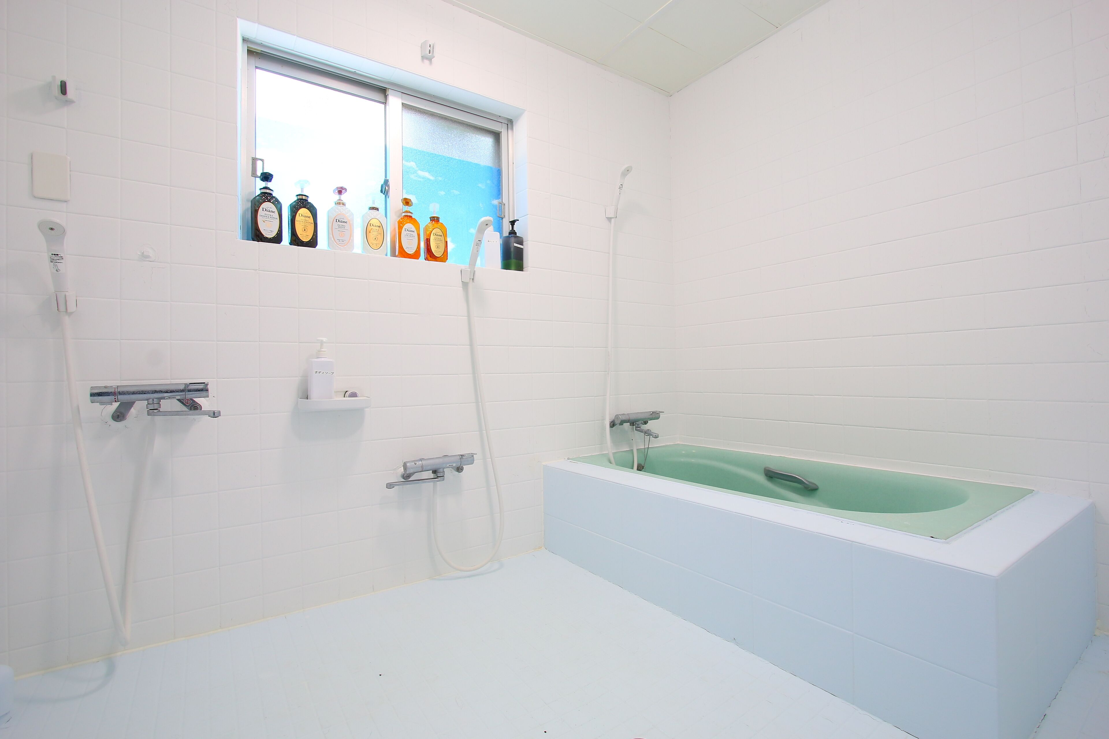 A bathroom with a bathtub, a window, and toiletries on the wall.