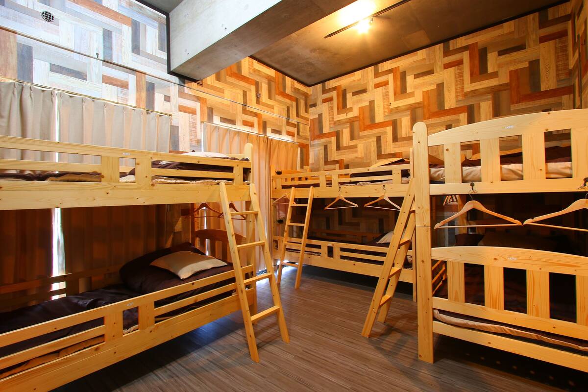 A room with bunk beds, wooden walls, and a hanging clothes rack.