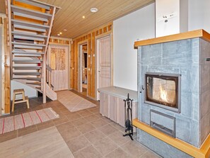 A modern interior with a stone fireplace, wooden staircase, and a view of the outdoors.