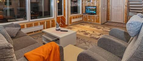 A cozy living room with a sofa, a coffee table, and a television.