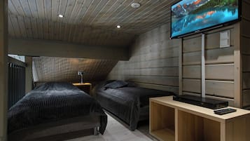A room with two beds, a TV on the wall, and a wooden ceiling.