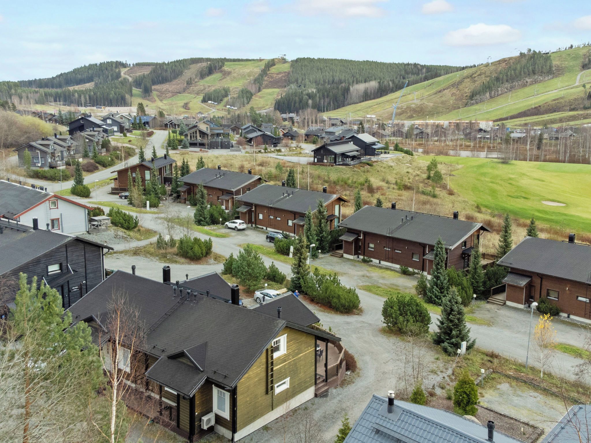 Una zona residencial con varias casas, un campo de golf y terreno montañoso al fondo.