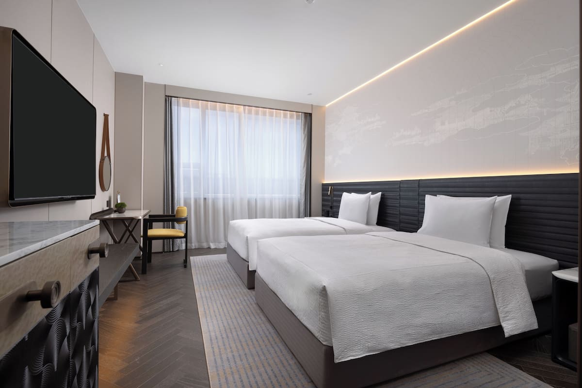 A modern hotel room with a large bed, a desk, and a television.