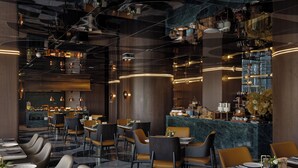 Un restaurante moderno con zona de bar, suelo de mármol y mobiliario contemporáneo.