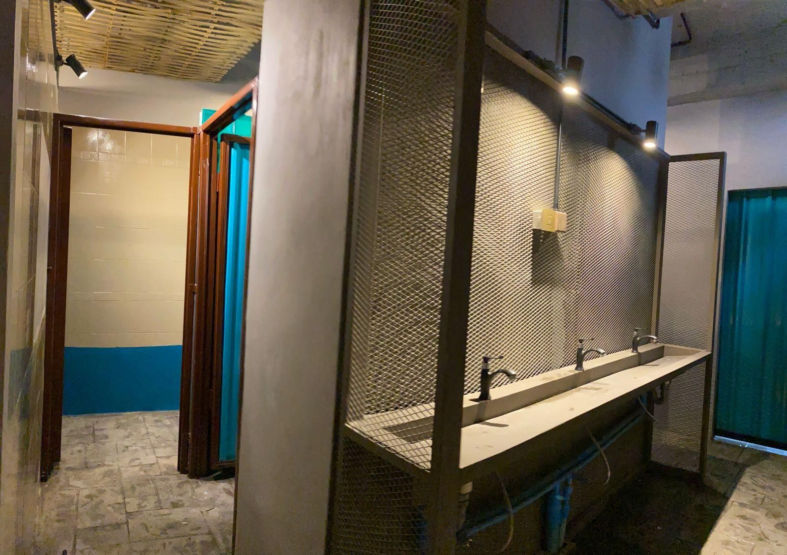 A restroom with a metal partition, a sink, and a mirror.