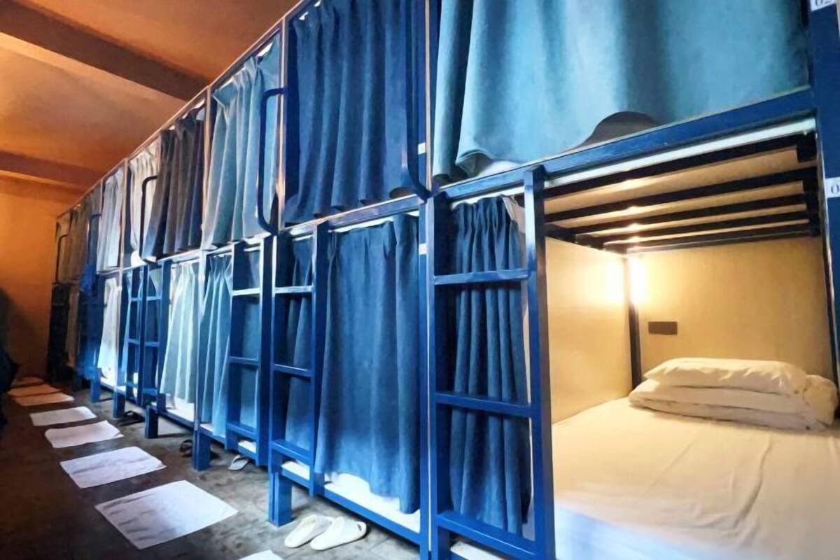 Filetta di letti a castello con tende, un letto con un cuscino e fogli sparsi sul pavimento.