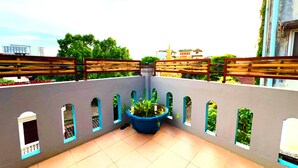 A rooftop terrace with a blue planter, tiled floor, and a view of buildings and trees. - TT Premium Hostel Vientiane (Vientiane)