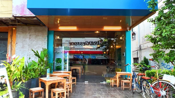 Un restaurant avec une terrasse, un panneau indiquant la possibilité de louer des vélos et un auvent bleu.