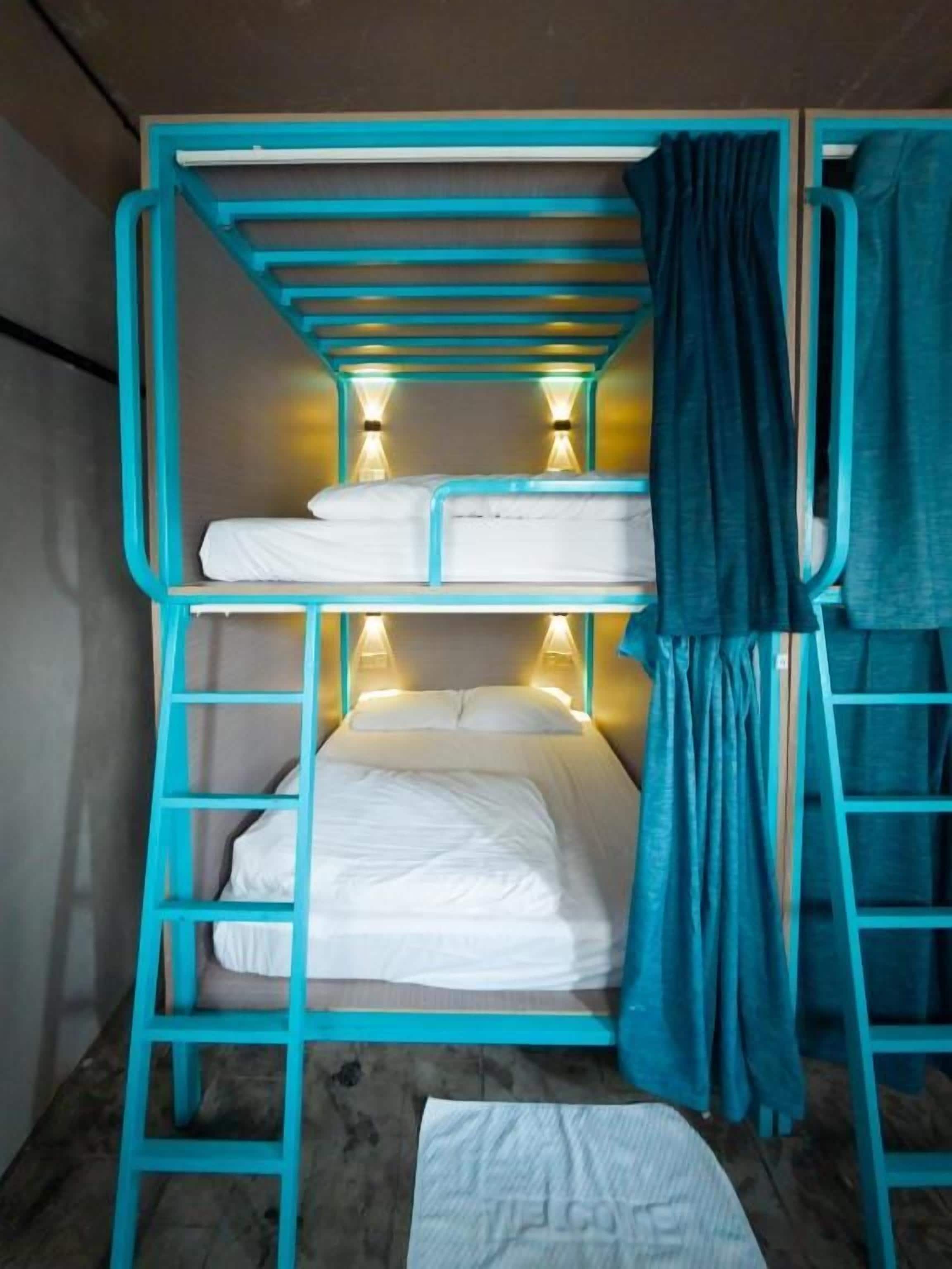 A bunk bed with a ladder, a curtain, and two wall-mounted lights.