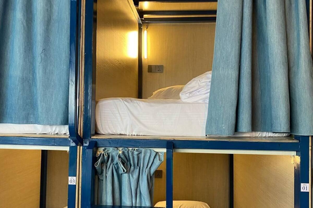 Una camera con letto a castello, tende e una lampada fissata al muro.
