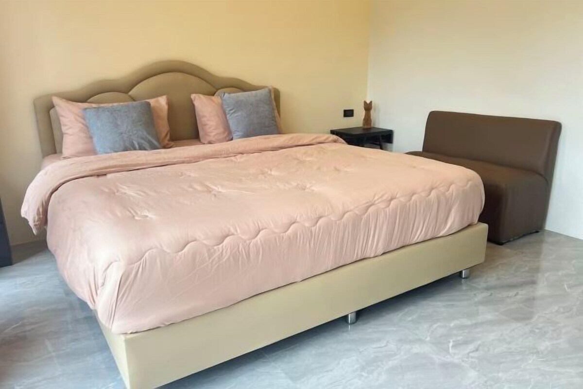 A bedroom with a bed, a nightstand, and a chair.