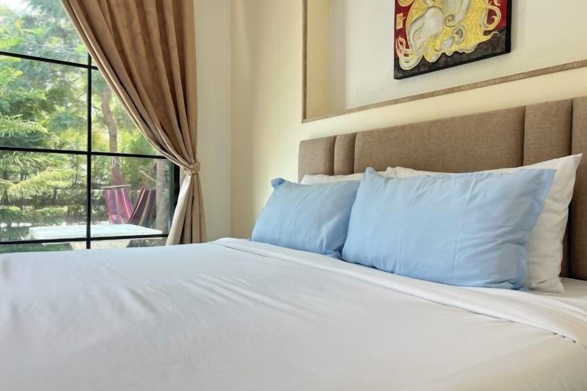 Een hotelkamer met een bed, een raam met gordijnen en een schilderij aan de muur.