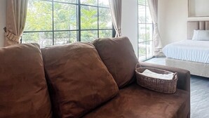 Un dormitorio moderno con un ventanal grande, un sofá marrón y una cama.