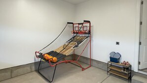 A basketball hoop in a room with a concrete floor, a door, and a small table with shoes and a blue container. - Charming 3-bedroom townhome with WiFi, AC in wonderful Washington (Washington)
