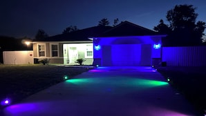 A house with a garage illuminated by blue lights.
