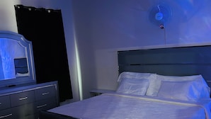 A bedroom with a bed, a bedside table, a dresser, and a ceiling fan.