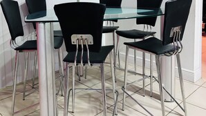 A conference room with a glass table and black chairs, a whiteboard, and a winter forest painting on the wall.