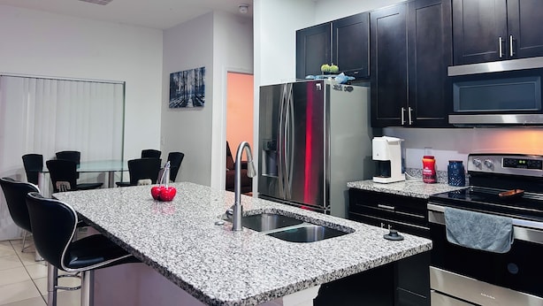 A modern kitchen with granite countertops, stainless steel appliances, and dark cabinetry.