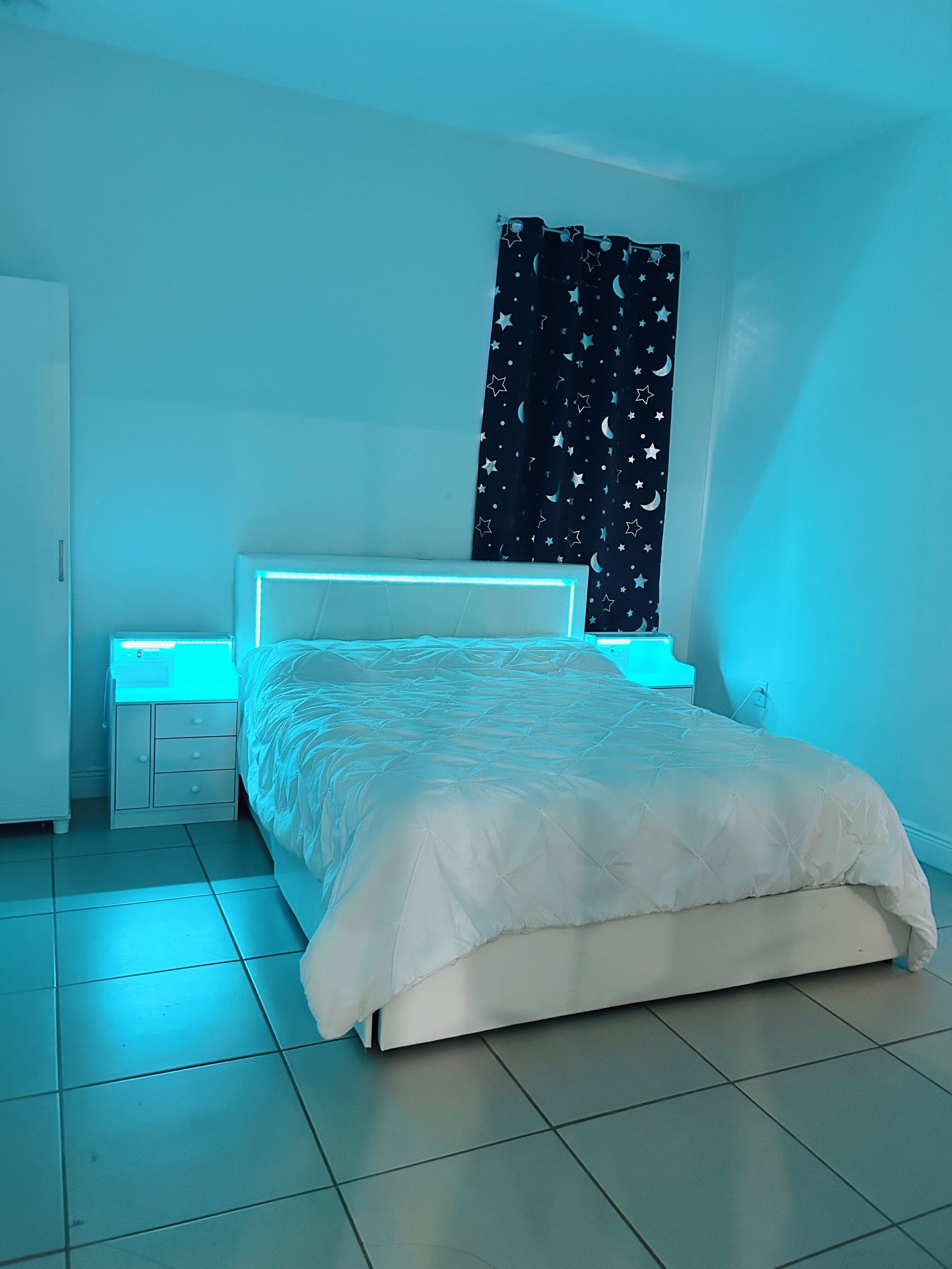 A bedroom with a bed, a nightstand, and a wall-mounted light.