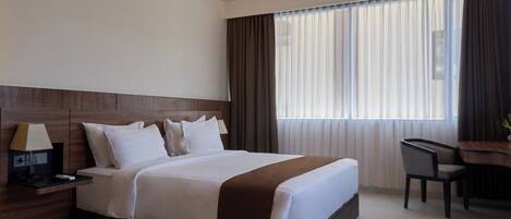 Una habitación de hotel moderna con una cama grande, un escritorio y una silla.