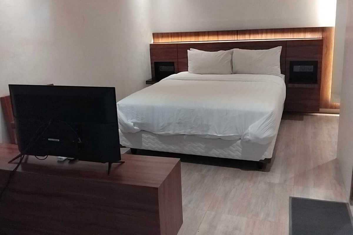 A modern hotel room with a large bed, a flat-screen TV, and a wooden nightstand.
