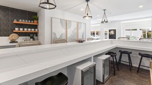 A modern kitchen with a large island, pendant lighting, and a view of the outside.
