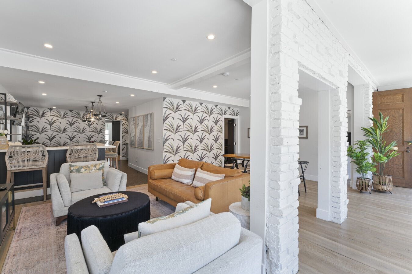 A spacious living room with a modern design, featuring a sofa set, a coffee table, and a dining area with a wooden table and chairs.