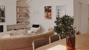 A modern living room with a high ceiling, a round dining table, and a comfortable seating area. - Isola Gerroa (Gerroa)