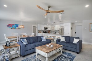 Ein modernes Wohnzimmer mit zwei Sofas, einem Couchtisch und einem Essbereich mit Stühlen und einem Tisch.