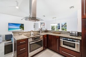 Una cocina moderna con encimeras de granito, electrodomésticos de acero inoxidable y armarios de madera.