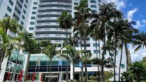 Un hotel de varios pisos con fachada de vidrio moderna, rodeado de palmeras.