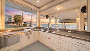 A kitchen with a view of the ocean, a sink, cabinets, and a countertop.