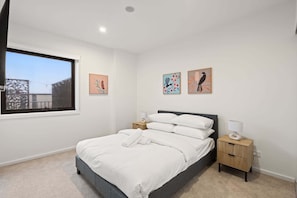 Un dormitorio con cama, mesitas de noche y decoración en la pared.