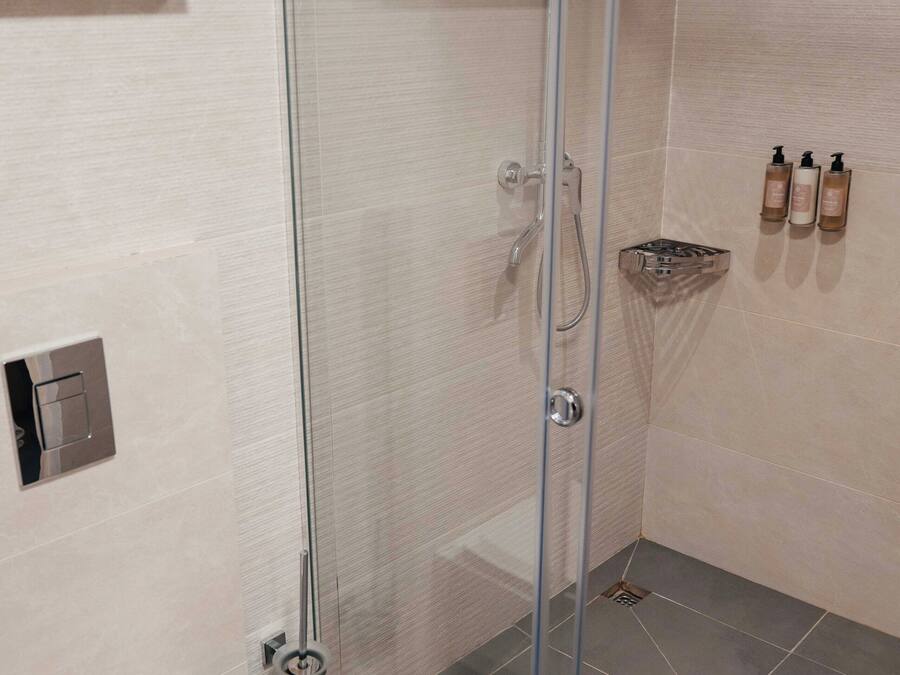 Ein modernes Badezimmer mit Duschkabine aus Glas, Toilette und Ablage für Toilettenartikel.