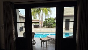 A room with a view of a swimming pool, a small table, and a chair.