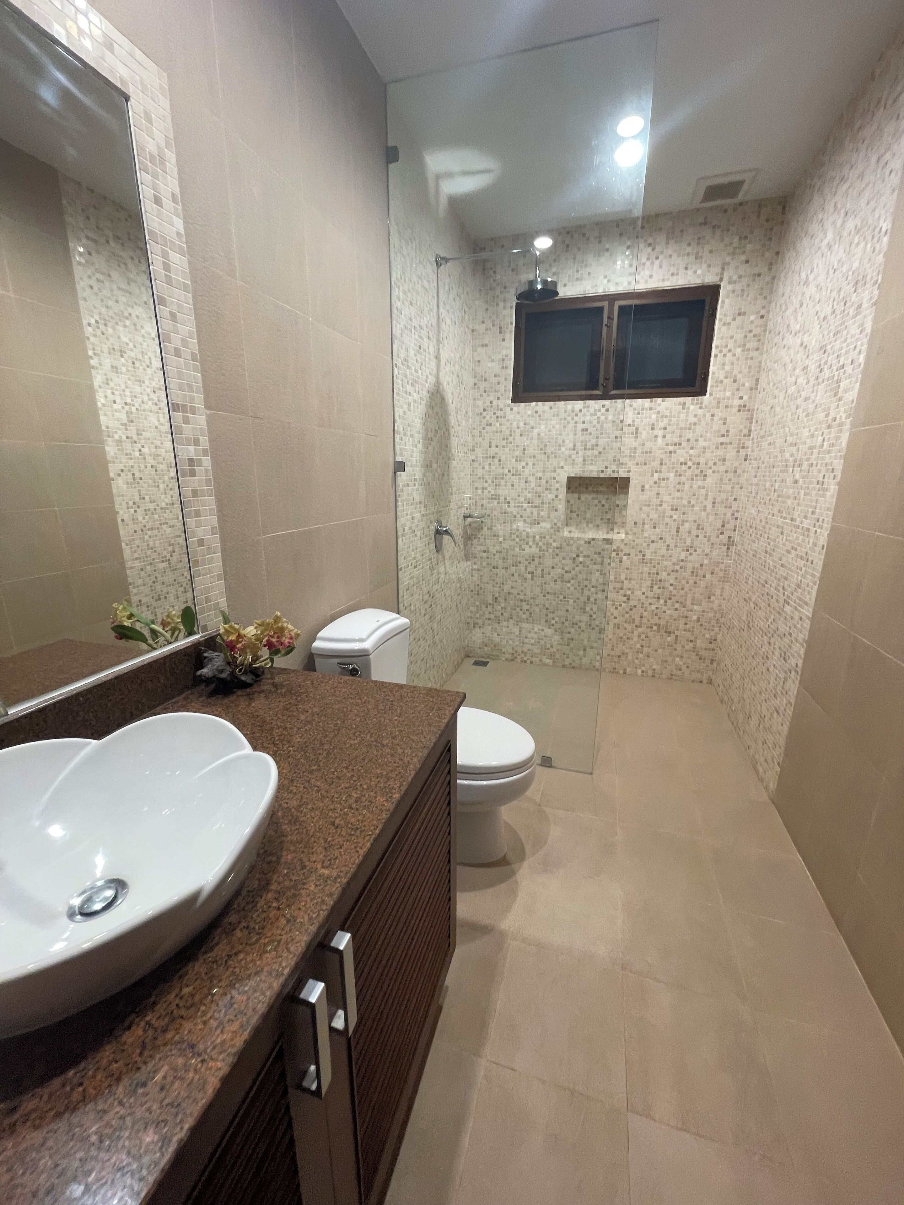 A bathroom with a large sink, toilet, and shower area.