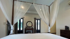 A bedroom with a large bed, a mirror, and a small table with an elephant figurine.