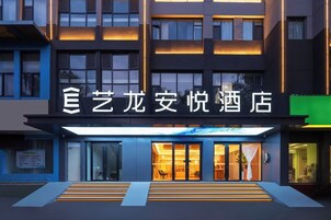 Una entrada de hotel moderna con señalización iluminada y una escalera que conduce al vestíbulo.