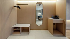 A compact, modern bathroom with a wooden vanity, a mirror, and a small seating area. - Elong Anyue Hotel (Xi'an)