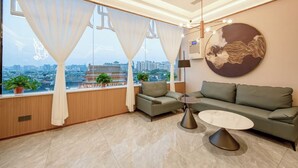 A modern living room with a sofa, a coffee table, and a view of the cityscape through large windows. - Elong Anyue Hotel (Xi'an)