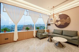 Una sala moderna con un sofá, una mesa de centro y vistas de la ciudad a través de amplios ventanales.