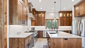 A modern kitchen with wooden cabinets, stainless steel appliances, and a large island.