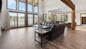 A spacious living area with a large sectional sofa, a dining table, and multiple windows offering a view of the outdoors.