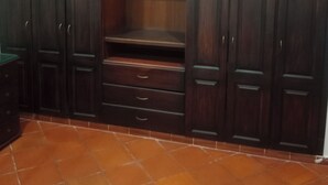 Una stanza con mobili in legno scuro, pavimento piastrellato e trave a soffitto bianca.