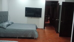 Camera da letto con due letti, una televisione montata a parete e una ventola a soffitto.