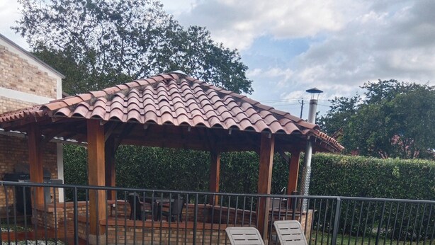 Una piscina con forma a stella, circondata da un solarium piastrellato. Sono presenti due lettini e un gazebo con tetto in piastrelle.