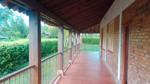 Un corridoio coperto con pavimento in piastrelle rosse, travi in legno e ringhiere in metallo.