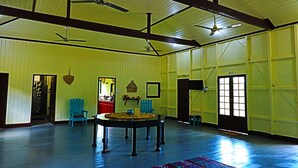 Um quarto amplo com tetos altos, vigas de madeira e uma grande mesa no centro.